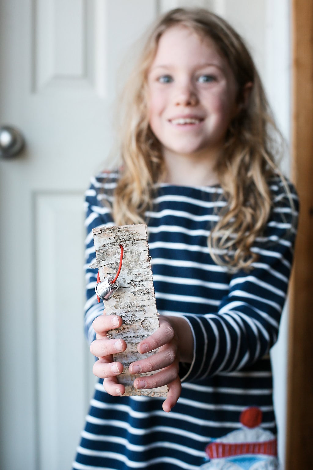 A child making a bookmark from birchbark and red cord and a thimble - a creative idea for teaching THE BIRCHBARK HOUSE by Louise Erdrich